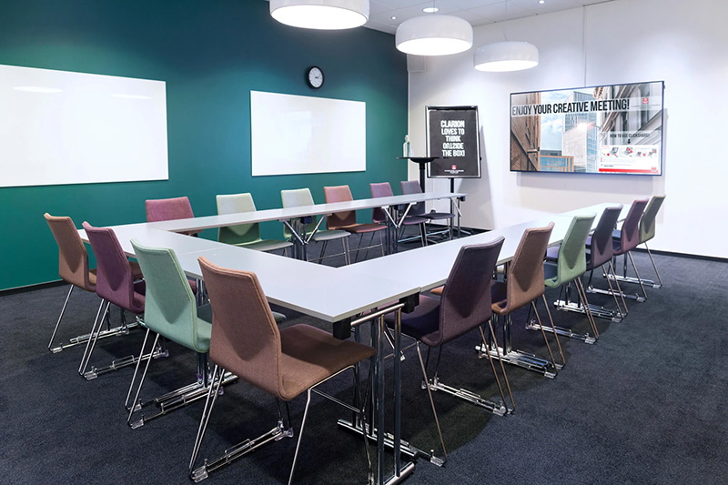 En bartender dekorerar tre cocktails i stora vinglas med is och limeklyftor på en bardisk. Dryckerna har en rödaktig färg och serveras i en livlig bar- eller restaurangmiljö.